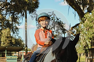 Caucasian boy wearing helmet and riding horse in greenery field