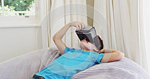 Caucasian boy wearing vr headset while lying on the bean bag at home