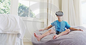 Caucasian boy wearing vr headset while sitting on the bean bag at home