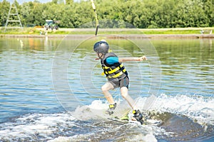Caucasian boy of 10 years old in a protective suit, active wakeboard training with fun activities in water sports adventure,
