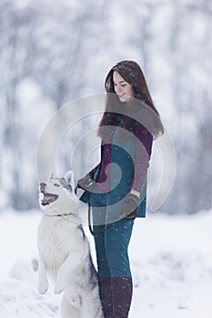 Caucasian Brunette Woman Keeping Her Husky Dog on a Short Leash During a Stroll in Winter Time