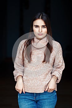 Caucasian brunette young beautiful girl woman model with long dark hair and brown eyes in turtleneck sweater and blue jeans