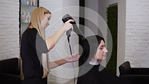 Caucasian brunette young woman get her hair dry by beautician barber after before the new haircut in hairdresser salon
