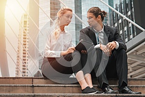 Caucasian business couple sitting together and having business discussion outdoor