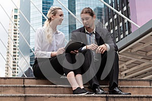 Caucasian business couple sitting together and having business discussion outdoor