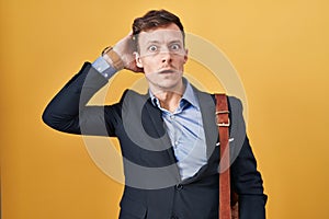 Caucasian business man over yellow background crazy and scared with hands on head, afraid and surprised of shock with open mouth