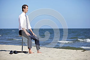 Caucasian business man resting, sitting on pneumatic stool on the beach