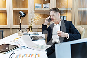 Caucasian business manager using phone to call customer while analyzing the sales report from marketing team for business income