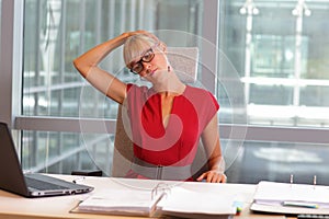 Caucasian business woman in eyeglasses relaxing neck