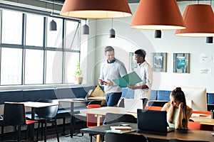 Caucasian businessman and african american colleague discussing strategy over file in office