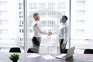 Caucasian businessman and African business man agreed contract and shaking hands in agreement.