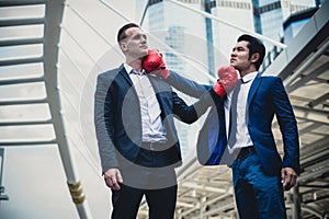 Caucasian businessman and asian businessman with red boxing gloves fighting by punch and uppercut. concept of business competition