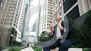 Caucasian businessman listening relaxing music while hold mobile phone. Urbane.
