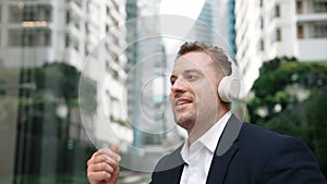 Caucasian businessman listening relaxing music while hold mobile phone. Urbane.