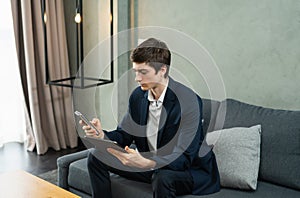 caucasian businessman seriously working with tablet and mobile phone, wear suit, sitting, looking at mobile, space at background.