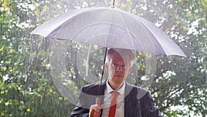 Caucasian businessman sheltering underneath an umbrella in the rain