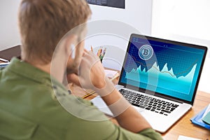 Caucasian businessman sitting at desk, using laptop with statistical data on screen photo