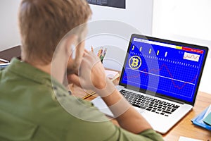 Caucasian businessman sitting at desk, using laptop with statistical data on screen photo