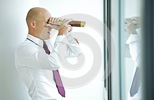 caucasian businessman spying using telescope thru office window