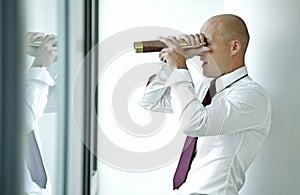 caucasian businessman spying using telescope thru office window