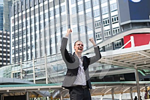 Caucasian businessman stand and raising up two hands to cheerful and celebrated his successful in mission.
