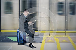 Caucasian businessman using a laptop in train station