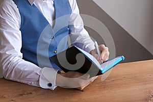 Caucasian businessman writing in notebook, male hands holding pen making notes