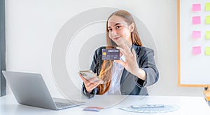 Caucasian businesswoman hand hold mock-up credit card for online shopping on smartphone or laptop computers from home office,