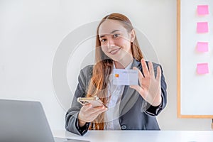 Caucasian businesswoman hand hold mock-up credit card for online shopping on smartphone or laptop computers from home office,