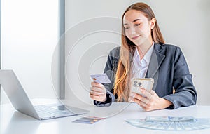 Caucasian businesswoman hand hold mock-up credit card for online shopping on smartphone or laptop computers from home office,