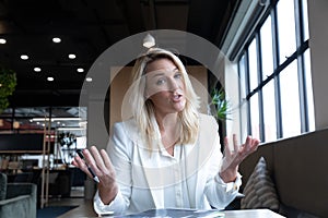 Caucasian businesswoman sitting having video chat going through paperwork in modern office