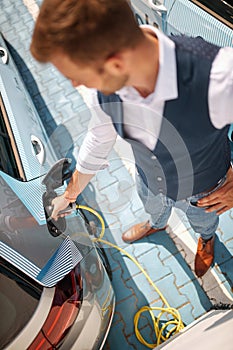 Caucasian busnessman charging his electric car