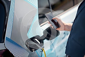 Caucasian busnessman waiting for his electric car to charge