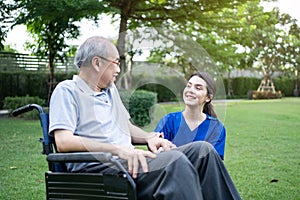 Caucasian Caregiver doctor talk with older disabled man on wheelchair. Attractive nurse taking care of senior elderly mature male