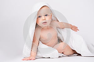 Caucasian, cheerful child looking at the camera. Smiling boy with a towel on his head. After bathing. White background.