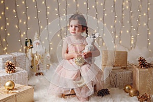 Caucasian child girl with brown eyes sitting with toys celebrating Christmas or New Year