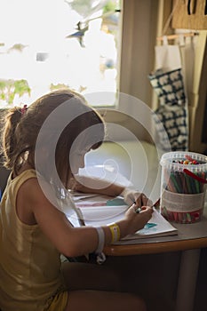 Caucasian child girl drawing with markers in a motorhome or campervan