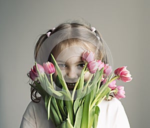 Caucasian child girl holding bouquet of tulips,spring season. Kid portrait with flowers.Mother's day