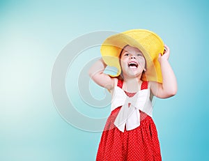 Caucasian child girl portrait in yellow hat and red dress on blue background empty copy space.Summer concept kid vocation design