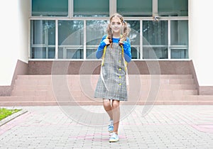 Caucasian child girl with yellow backpack at school yard outdoors.Back to school.Pupil portrait