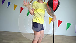 Caucasian child hitting punching bag. Active playful girl have fun at home