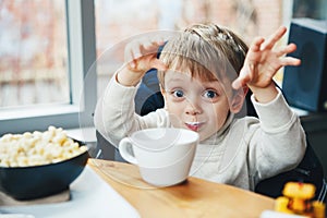 Caucasian child kid boy drinking milk from white cup eating breakfast lunch