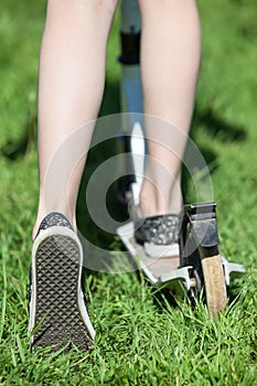 Caucasian child riding puch scooter on green grass, close up view