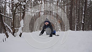 Caucasian child runs through deep snow, jumps, falls to his knees