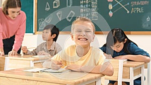 Caucasian child smiling at camera while doing classwork at classroom. Pedagogy.