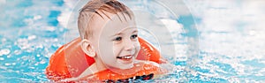 Caucasian child in swimming pool. Preschool boy  training to float with red circle ring in water.
