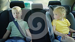 Caucasian children in child seats sleeping while traveling in a car.