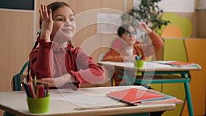 Caucasian children classmates little girl kid child and boy kids raising hands while teacher ask question lesson