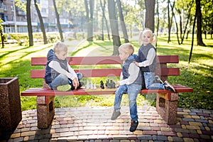 Caucasian children play chess on wooden chessboard in park bench. Brothers and sister big friendly active mental family spend time