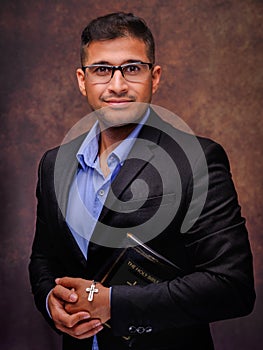 Caucasian christian man with glasses in business suit holding holy bible with jesus cross